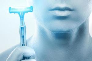 Young man using sharp safety razor for a shaving routine photo