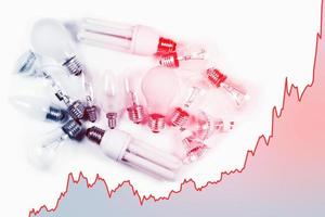 Light bulbs and rising chart representing current electricity price during energy crisis in the world photo