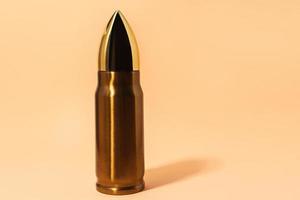 Big and shiny bullet against beige background photo