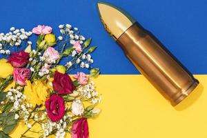 Pacifism and non-violence movement. Bullet and bunch of different flowers and Ukrainian flag.