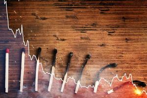 Undamaged and several progressively more burnt out match sticks and falling sparkline chart photo
