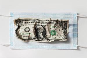 billete de un dólar arrugado en una máscara facial higiénica desechable. foto