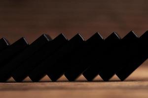 Closeup shot of chain reaction of black domino tiles falling. photo