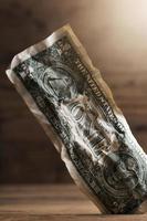 Closeup shot of a crumpled one dollar bill stuck in a gap in the floor. photo