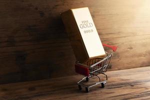 Large shiny gold bar put in a tiny shopping cart. photo