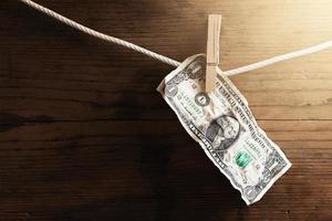 One dollar bill is drying on a white rope, held by laundry pin. photo