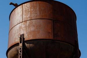 Old rusty water tower on blue sky background photo