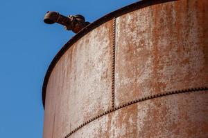 Old rusty water tower on blue sky background photo