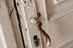 Old shabby door handle on the white door photo