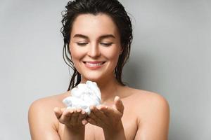 Young and beautiful woman with cleansing foam in her hands photo