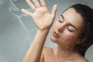 Portrait of sensual woman captured through wet glass photo