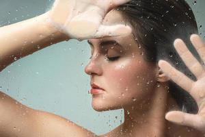 Portrait of sensual woman captured through wet glass photo