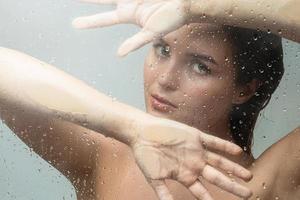 Portrait of sensual woman captured through wet glass photo