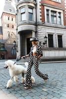 Stylish woman wearing polka dot suit walking with the white Poodle photo