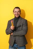 hombre alegre con gafas sosteniendo grandes penci sobre fondo amarillo foto