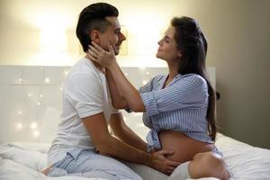 Young couple are waiting for a baby. Husband and his pregnant wife relax on the bed. photo