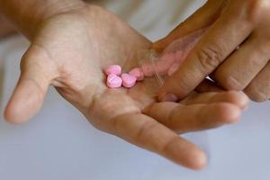 Man pouring heart shaped pills on palm from ziplock bag. photo