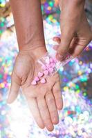 Man pouring heart shaped pills on palm from ziplock bag. photo