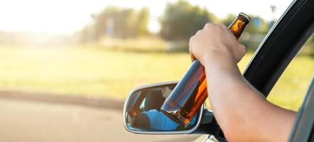 conductor de auto sosteniendo una botella de cerveza foto