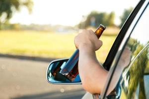 conductor de auto sosteniendo una botella de cerveza foto