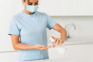 Woman using hand sanitizer or liquid soap for hands disinfection at home photo