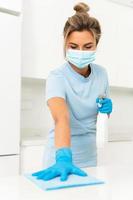 Woman worker wearing prevention mask and gloves during apartment cleaning photo