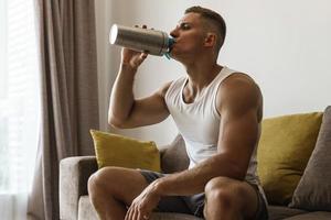 hombre bebiendo batido de proteínas después de hacer ejercicio en casa foto