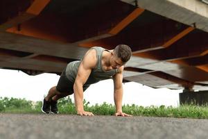 Muscular man is doing push-ups during calisthenic workout on a street photo