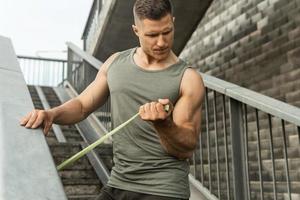 Muscular man during workout with a resistance rubber band on a street photo