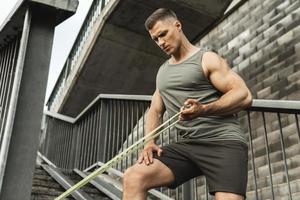 Muscular man during workout with a resistance rubber band on a street photo