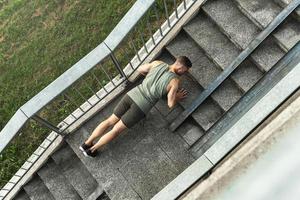 Muscular man is doing push-ups during calisthenic workout on a street photo