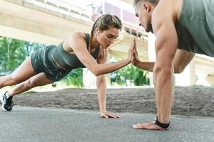 Athletic couple and fitness training outdoors. Man and woman doing push-ups exercise. photo