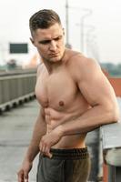 hombre musculoso con el torso desnudo durante el entrenamiento físico en un puente foto