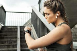 Athletic woman using smartwatch during her fitness workout on city street photo