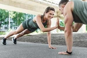 Athletic couple and fitness training outdoors. Man and woman doing push-ups exercise. photo