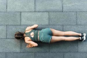 Athletic woman is doing push-ups during calisthenic workout on a street photo