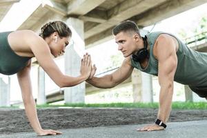 Athletic couple and fitness training outdoors. Man and woman doing push-ups exercise. photo