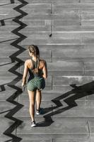 Sportive woman is running upstairs by a concrete staircase photo