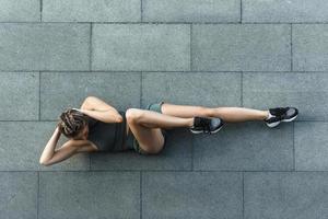 mujer atlética haciendo ejercicios abdominales en piso de concreto foto