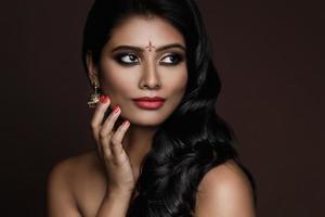 retrato de mujer india con hermoso maquillaje y peinado sobre fondo marrón foto