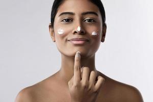 bella mujer india aplicando crema hidratante en la cara foto