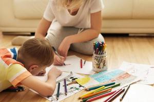 Happy mother and son are drawing together at home photo