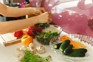 mujer está cocinando ensalada vegetariana con verduras frescas