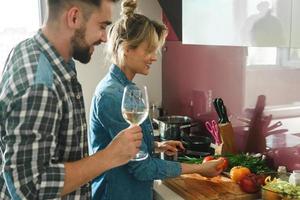 Happy couple cooking launch and drinking wine together in the kitchen photo