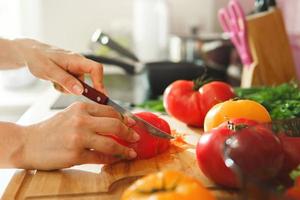 Woman is slicing red tomatoes on wooden chopping board photo