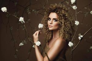 encantadora mujer joven con peinado afro y hermoso maquillaje con muchas flores blancas foto