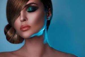 Model in stylish image with sleek hair covering one eye and beautiful green eyeshadows on another photo