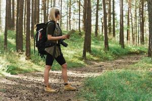 Female hiker with big backpack using map for orienteering in the forest photo