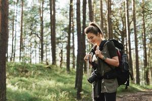 Hiker walking with a backpack and modern mirrorless camera in green forest photo