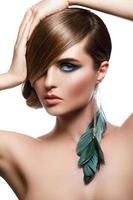 Model in stylish image with sleek hair covering one eye and feather earring photo